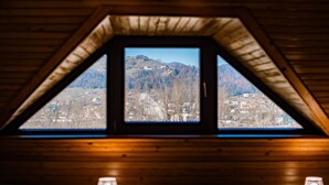 Um quarto com teto inclinado e janela com vista para uma paisagem montanhosa.