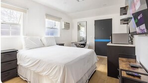 Een moderne hotelkamer met een groot bed, een bureau, een stoel, een spiegel en een tv aan de muur met diverse zenders.