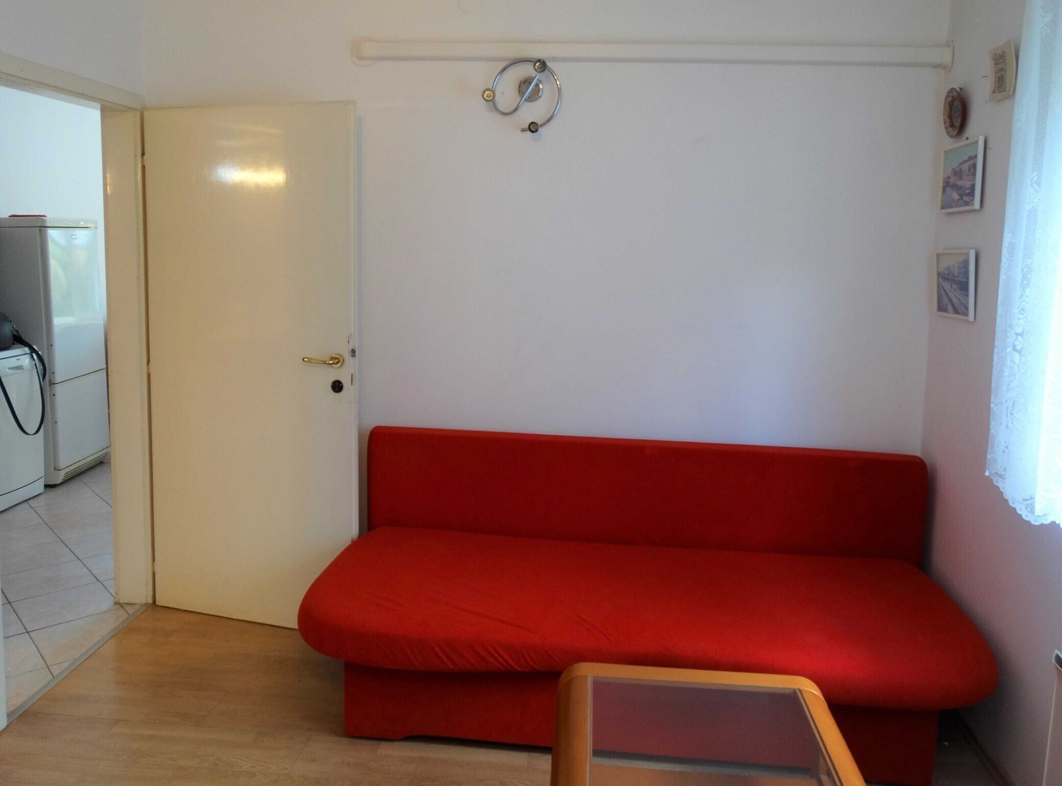 A room with a red sofa, a white door, and a small table.