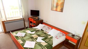 Ein Hotelzimmer mit Bett, Fernseher, Schreibtisch und Fenster.