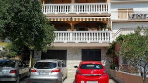 A two-story building with a balcony on the second floor. There are three cars parked in front. - Crikvenica Apartments and Rooms with Sea View - One Bedroom Apartment with Sea View (Crikvenica)