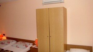 A bedroom with a wooden wardrobe, a bed with a floral duvet, and an air conditioning unit on the wall. - Crikvenica Apartments and Rooms with Sea View - One Bedroom Apartment with Sea View (Crikvenica)