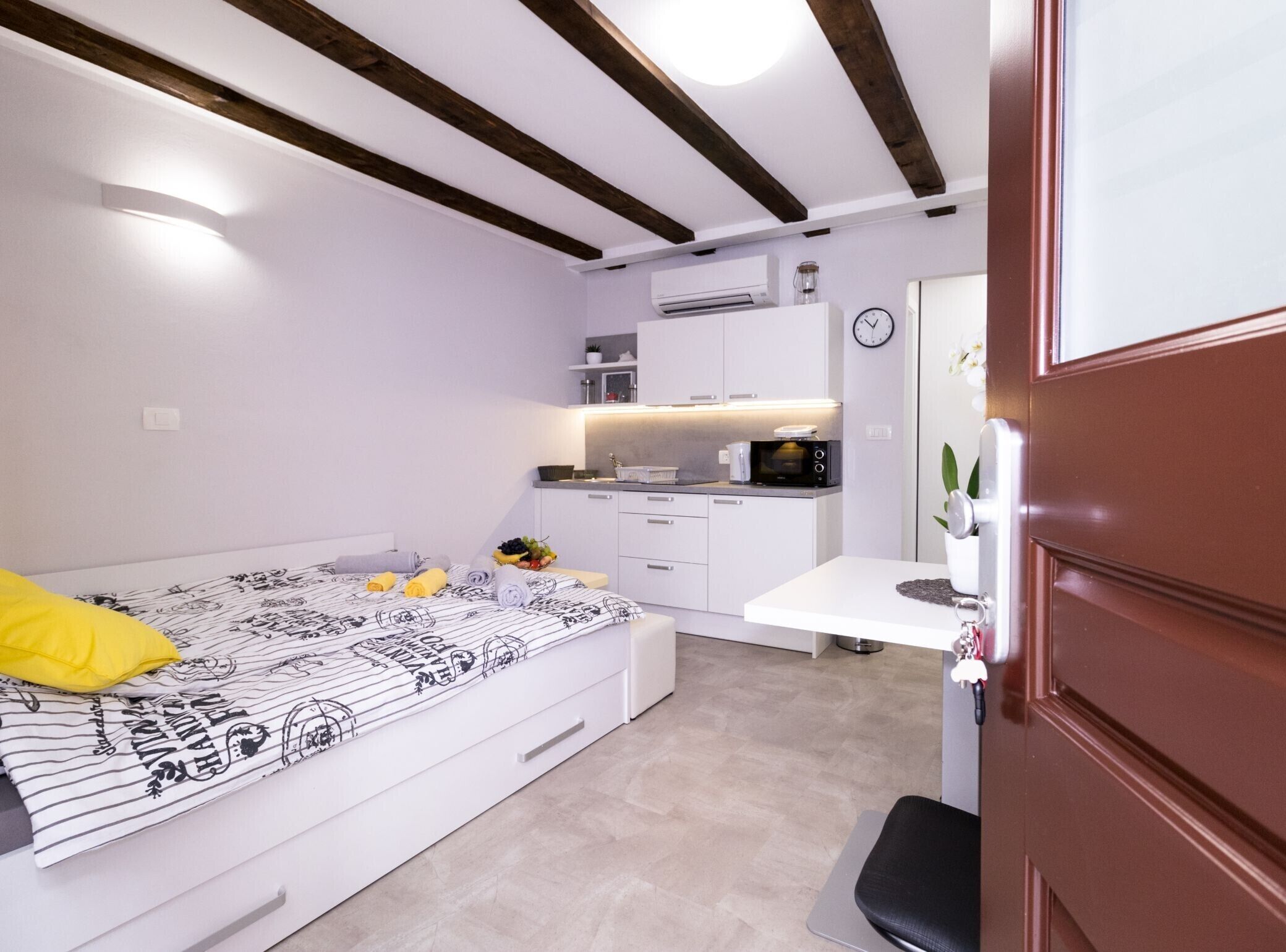 Una camera compatta con un letto, un comodino e un angolo cottura piccolo.