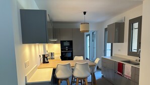 Una cocina moderna con una isla de madera, taburetes blancos y un horno empotrado.
