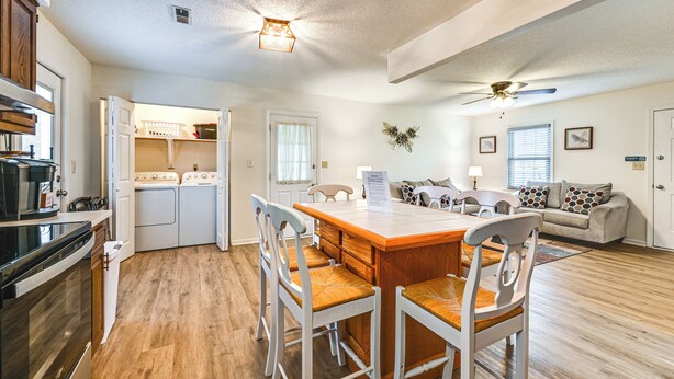 A spacious kitchen with wooden cabinets, a built-in oven, and a dining area with a wooden table and chairs. - Deck & Fenced Yard: Family Home in Winterville (Winterville)