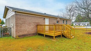 A single-story brick building with a wooden deck and stairs leading to a door. - Deck & Fenced Yard: Family Home in Winterville (Winterville)