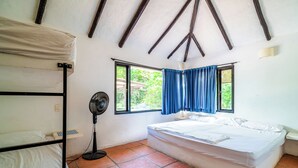 Una habitación con una cama individual, una litera, un ventilador y una ventana con cortinas azules.