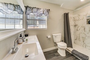 Et badeværelse med en hvid vask, toilet og brusebad.