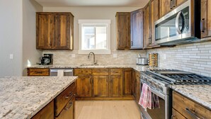 Una cocina con armarios de madera, estufa de acero inoxidable, microondas y ventana.