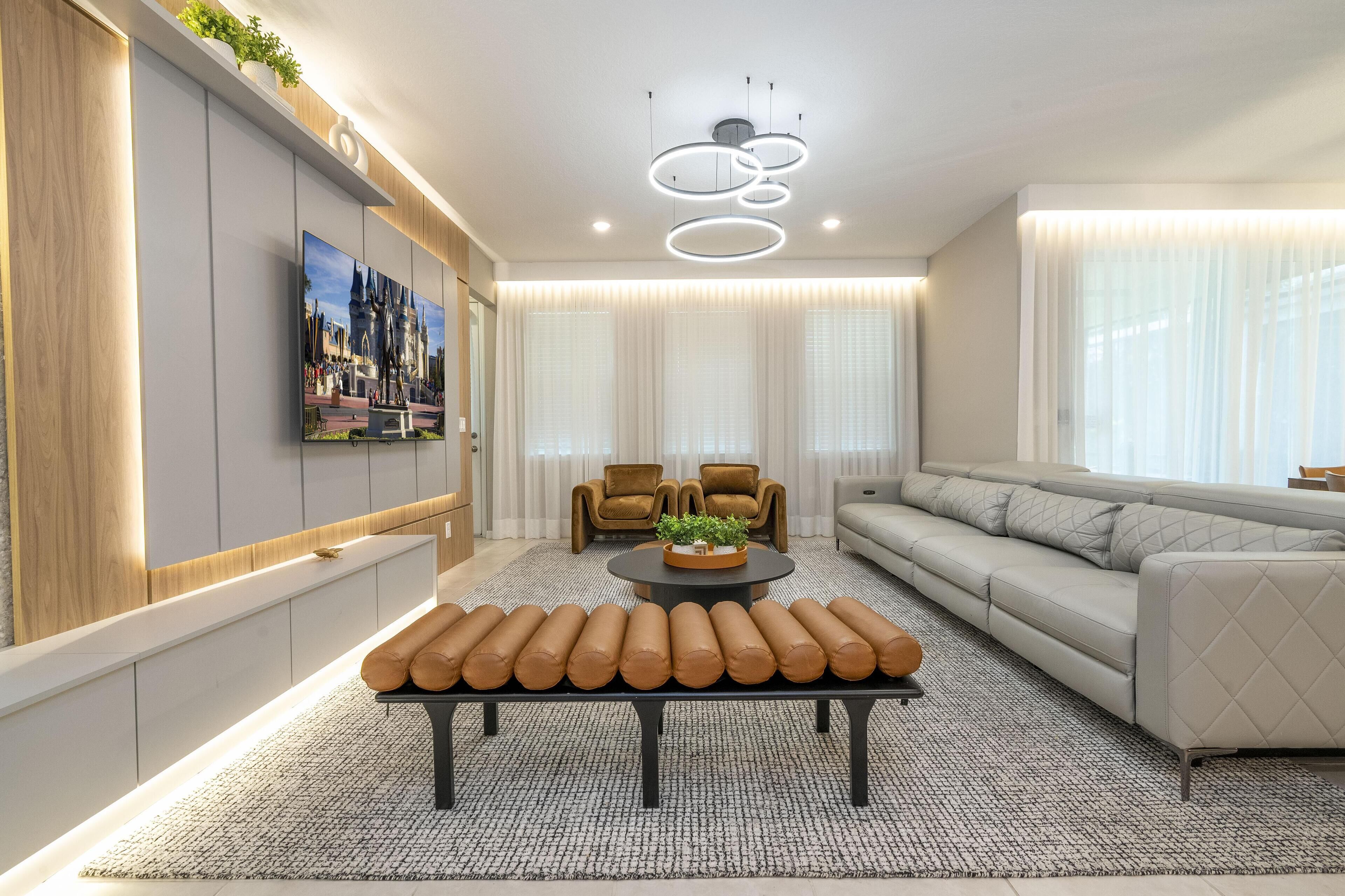 Un salon moderne avec un canapé, une table basse agrémentée d’une plante et un banc avec des coussins.