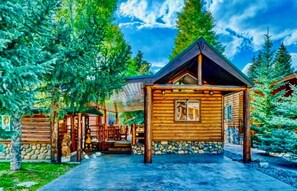 Una cabaña de troncos con cimientos de piedra, paredes de madera y techo inclinado.