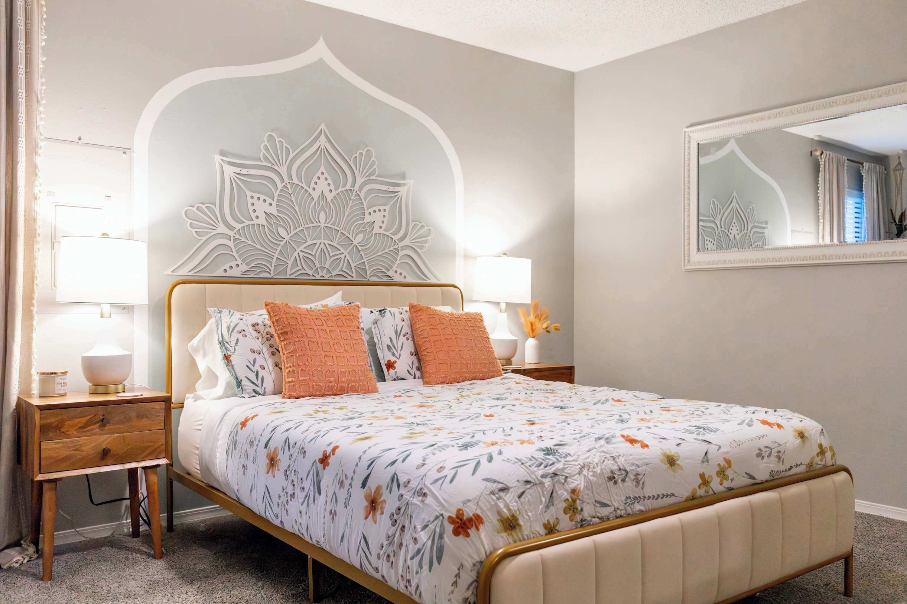 Un dormitorio con cama, mesitas de noche, un espejo y un adorno en la pared.