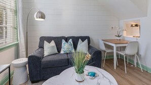 Una sala de estar moderna con un sofá gris, sillas blancas, una mesita y una lámpara de pie.