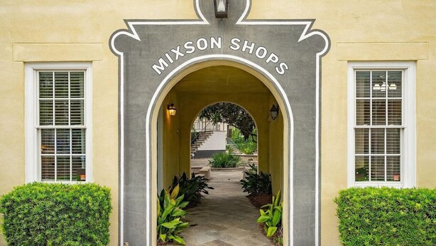Entrada de un edificio con un arco que dice 'MIXSON SHOPS' y un sendero que lleva a una escalera.
