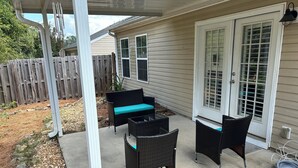 An outdoor patio area with a covered seating arrangement and a door leading to the house. - Charming 2-bedroom building in fabulous Augusta with AC, WiFi (Augusta)