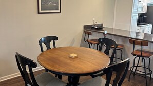 A dining area with a round wooden table, black chairs, a chandelier, and a kitchen in the background. - Charming 2-bedroom building in fabulous Augusta with AC, WiFi (Augusta)