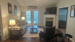 A living room with a sofa, a coffee table, a fireplace, and a television. - Charming 2-bedroom building in fabulous Augusta with AC, WiFi (Augusta)