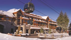 Un centro de esquí con un teleférico, edificios de madera y un paisaje cubierto de nieve.
