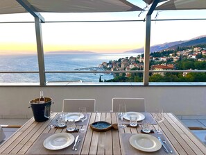 A table set for two with a view of the sea and a town in the background. - Blue View Residence (Opatija)