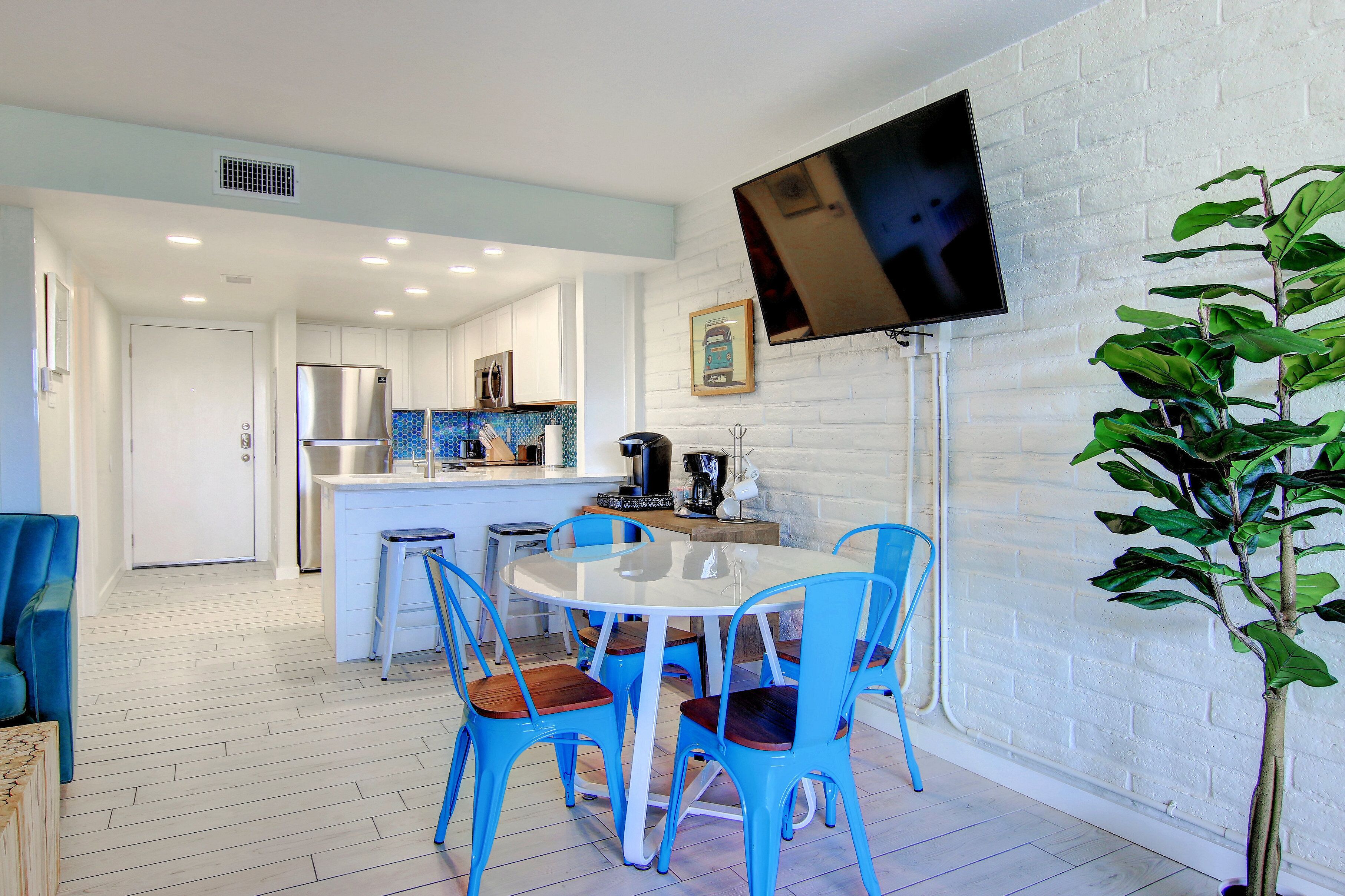 Una cocina moderna con armarios blancos, un refrigerador de acero inoxidable y un salpicadero de azulejos azules.