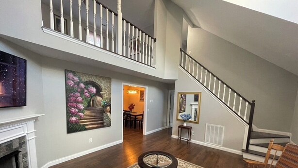 Un salón espacioso con chimenea, un tapete grande, una mesa de centro y una escalera que sube a un nivel superior.