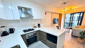 A modern kitchen with white cabinets, a built-in oven, and a large island. - Apartment in Barranco by Artline (Lima)