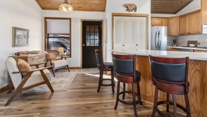 A modern kitchen with wooden cabinets, a stainless steel refrigerator, and a bar area with stools. - Mountain View Escape (Estes Park)