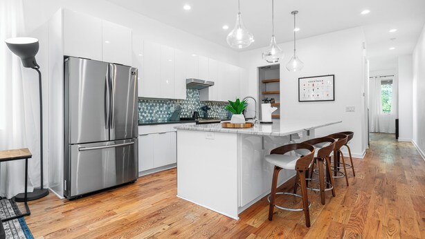 A modern kitchen with a stainless steel refrigerator, wooden bar stools, and pendant lighting. - Spacious ATL Escape, Prime Area Near Everything! 2 King Beds. Walkable & Central (Atlanta)
