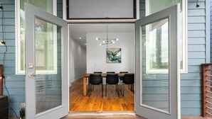 A modern dining area with a wooden table and black chairs, a hanging light fixture, and a painting on the wall. - Spacious ATL Escape, Prime Area Near Everything! 2 King Beds. Walkable & Central (Atlanta)