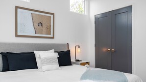A bedroom with a bed, pillows, a nightstand, a lamp, a framed picture, a wardrobe, and two windows. - Spacious ATL Escape, Prime Area Near Everything! 2 King Beds. Walkable & Central (Atlanta)