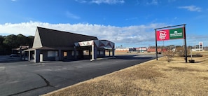 A Red Roof Inn with a large parking lot and a sign for Hometown Studios in the background. - HomeTowne Studios by Red Roof LaGrange (LaGrange)