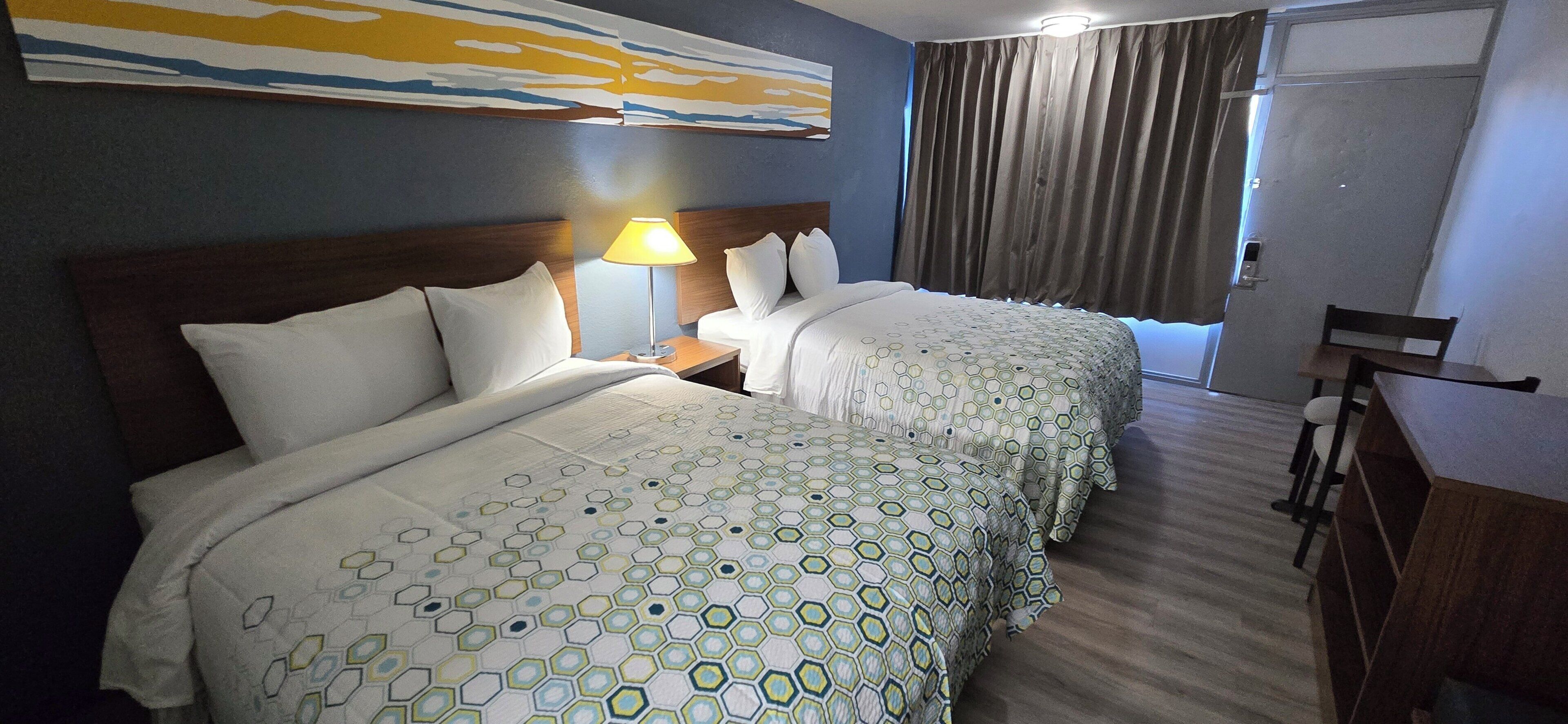 Een hotelkamer met twee bedden, een bureau en een stoel.