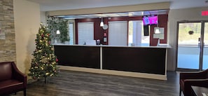 A reception area with a Christmas tree, a counter, and seating. - HomeTowne Studios by Red Roof LaGrange (LaGrange)