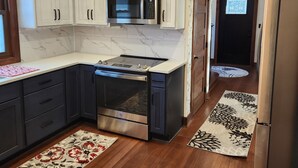 Una cocina moderna con gabinetes blancos, horno de acero inoxidable y microondas.