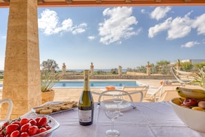 A table set for two with a bottle of wine, a glass, and a bowl of fruit.