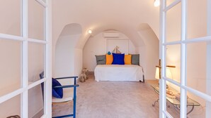 Une chambre à coucher avec un lit, une chaise, une table et un plafond en arc de cercle.