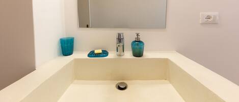 A bathroom sink with a mirror above it, a blue soap dish, and a blue soap dispenser.