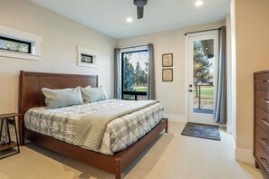 A bedroom with a wooden bed, a small bedside table, a dresser, and a door leading to a balcony.
