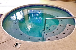 A hot tub with a tiled edge and a metal ladder.