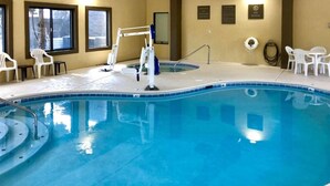 Una piscina interior con trampolín, sillas de descanso y señalización de seguridad.