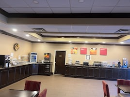 A breakfast area with a counter, seating, and a wall with menu boards.