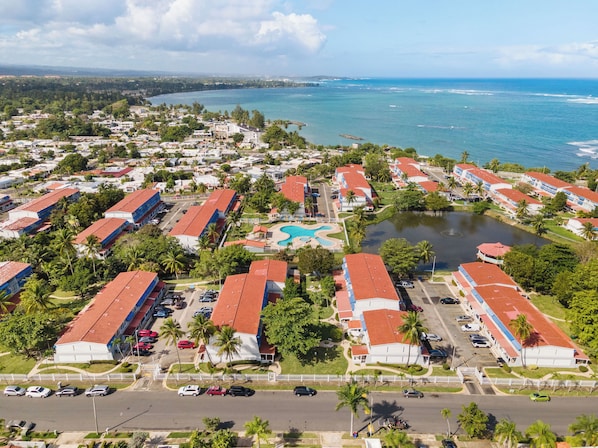 An aerial view of a coastal resort with multiple buildings, a swimming pool, and a marina.