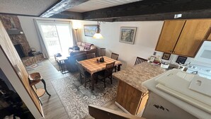 A kitchen with a wooden island, a dining area with a table and chairs, and a view of the living room through an open door. - Cozy 3-bedroom condo with fire place and WiFi in Fraser, CO (Fraser)