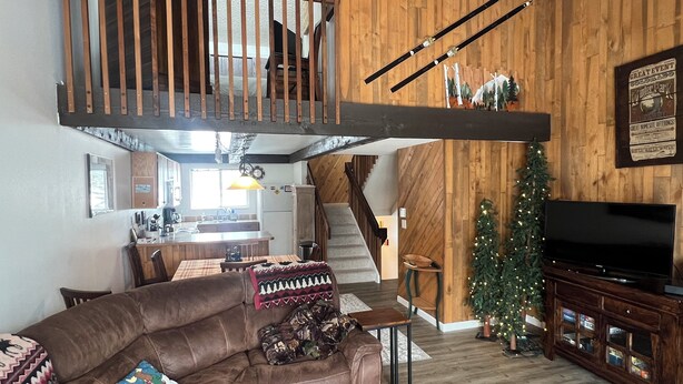 A spacious living room with a brown leather sofa, a wooden staircase, a kitchen area, and a Christmas tree. - Cozy 3-bedroom condo with fire place and WiFi in Fraser, CO (Fraser)