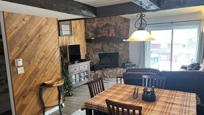 A cozy living room with a fireplace, wooden walls, and a plaid tablecloth. - Cozy 3-bedroom condo with fire place and WiFi in Fraser, CO (Fraser)