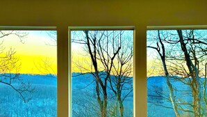 Three windows with a view of a forest and mountains.