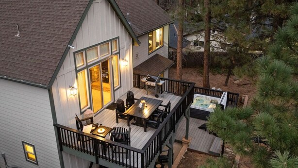 Une maison à deux étages dotée d’une terrasse, d’un espace salon extérieur et d’un jacuzzi.