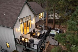 Une maison à deux étages dotée d’une terrasse, d’un espace salon extérieur et d’un jacuzzi.