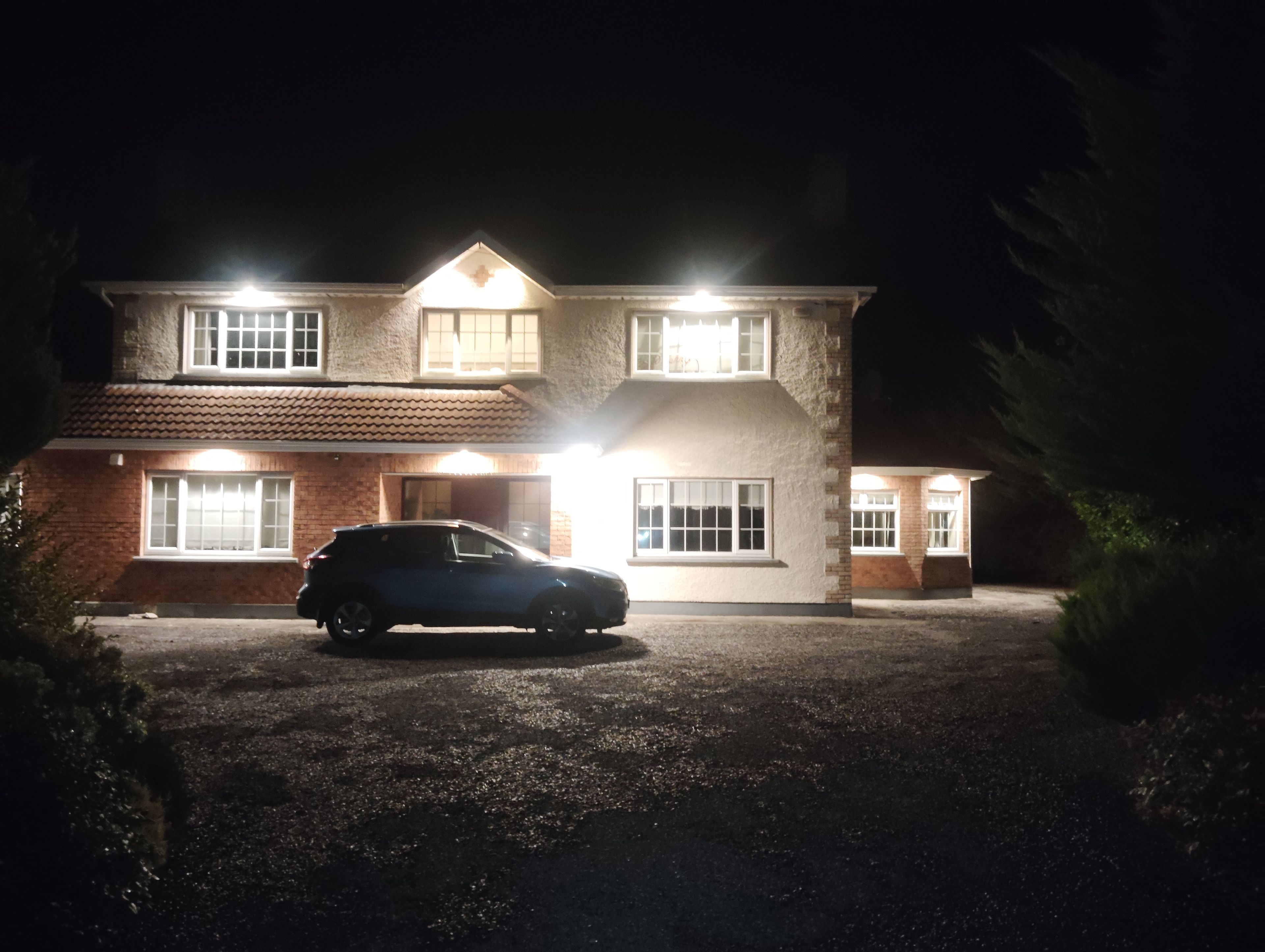 A two-story house with a car parked in the driveway at night.