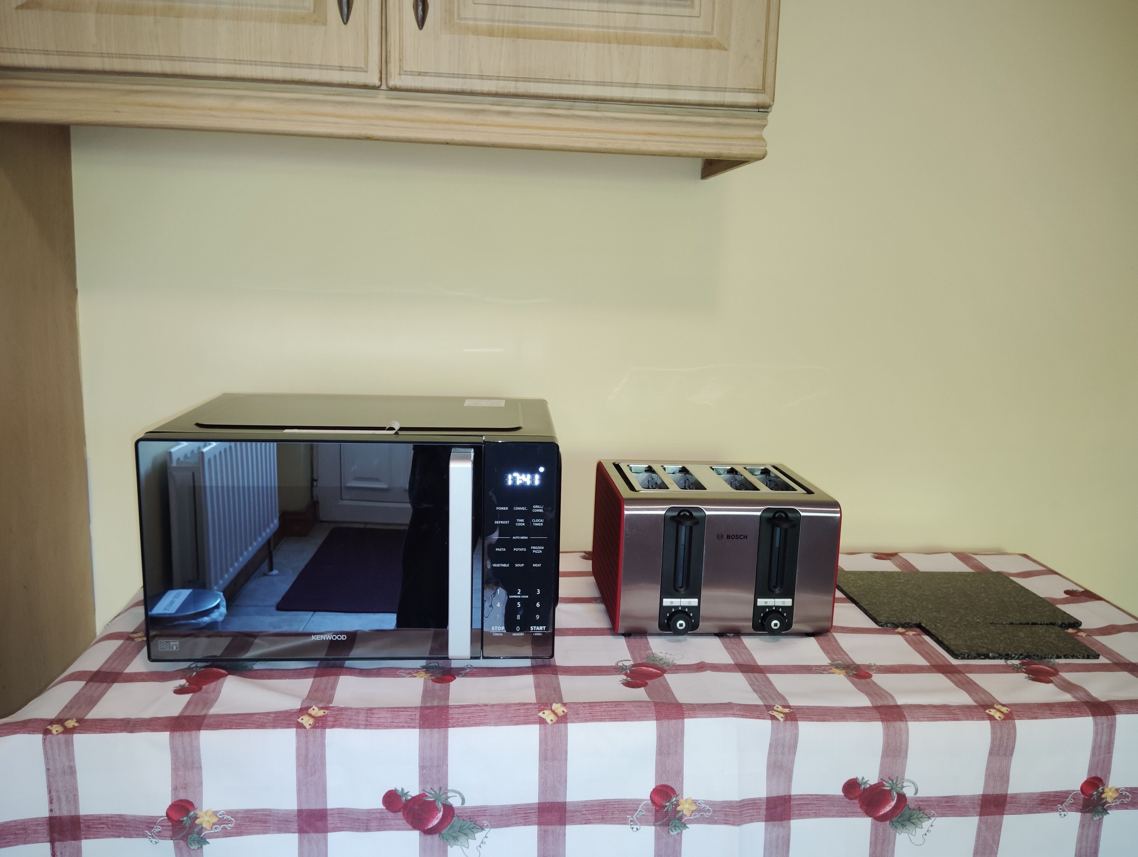 Une cuisine équipée d’un four à micro-ondes, d’un grille-pain et d’une nappe à carreaux.